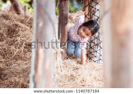 Cute asian child girl having fun to play with hay stack in the farm with happiness