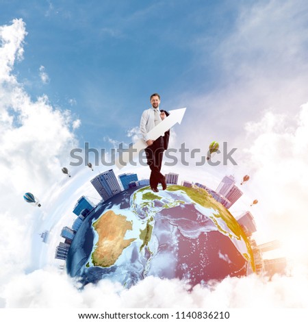 Conceptual image of young businessman in suit showing aside with big white arrow in his hand while standing on Earth globe and cloudy sky on background. Elements of this image are furnished by NASA.
