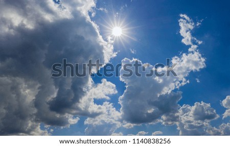 Panorama of a fragment of the sky with sun, cumulus and storm clouds
