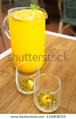 big glass jar with orange and passion fruit juice on a wooden background, space for text. colorful drinks. Natural fruit ingredients for drinks