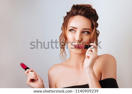 Portrait of a gorgeous young brunette woman in stylish makeup with lipsticks.