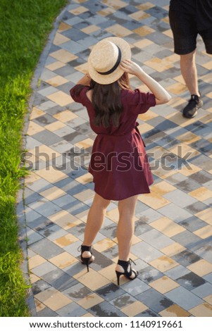 girl in a hat posing for a photographer outdoors. Back view