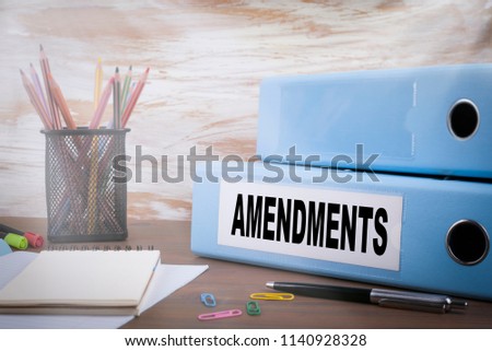 Amendments. Office Binder on Wooden Desk. On the table colored pencils, pen, notebook paper Royalty-Free Stock Photo #1140928328