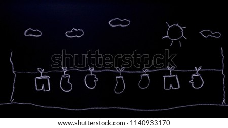 Little pants, gloves, socks being rope hanged on open ground with sun and cloud as background. Chalk drawing on black board. For Christmas concept