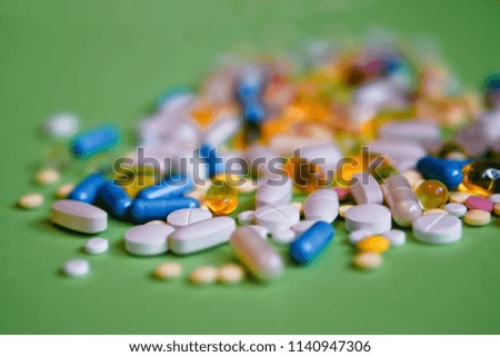 Assorted pharmaceutical medicine pills, tablets and capsules and bottle on green background. Drugs and various narcotic substances. Copy space for text. Stock photo for design