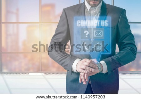 Businessman using modern smartwatch contact us on virtual hologram 