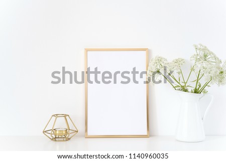 Gold frame mock up with a Aegopodium in jug and candle. Mockup for headline design.Template for lifestyle bloggers,media