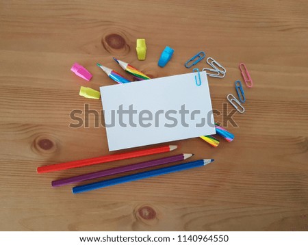 Blank paper with colored pencils, erasers and paper clips laying on a wooden desk, School and Office supplies, Back to school, Writing and drawing utensils