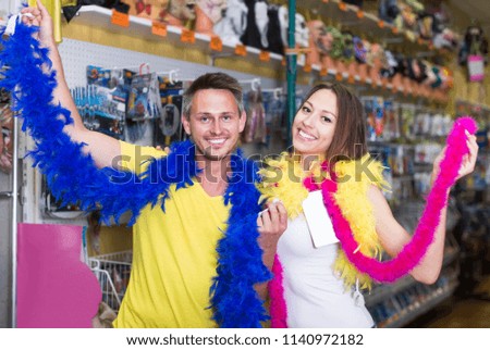 
Smiling young couple measuring the colorful boa in the store