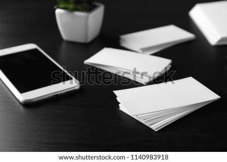 Blank business cards with mobile phone on dark table