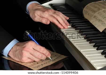 man hands playing piano and writes on parer for notes Royalty-Free Stock Photo #114099406