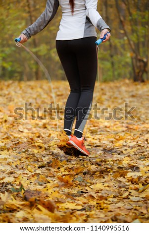 Image from back of sports girl in sneakers jumping with rope