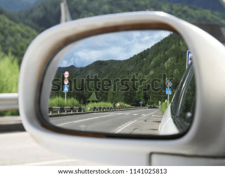 reflection of the road and mountains in the mirror of the car