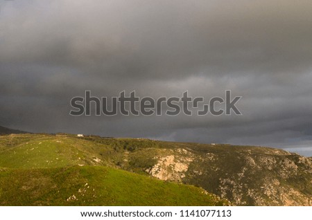 Lonely houses located on the top of the hill on dramatic dark sky background.