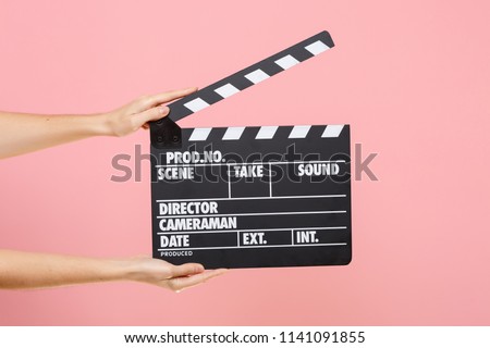 Close up female holding in hand classic director clear empty black film making clapperboard isolated on trending pastel pink background. Cinematography production concept. Copy space for advertising