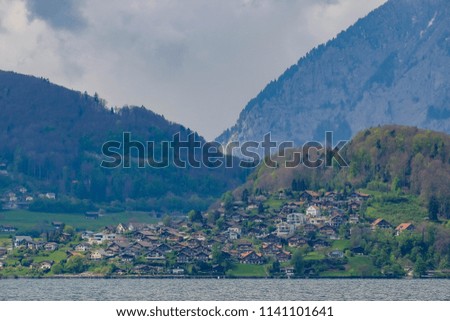 Landscape of Alps and Switzerland Village in the forest in the cloudy day. Pier in front of the city. Blue Clouds.