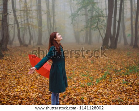woman with umbrella in the forest in autumn nature foggy weather rain