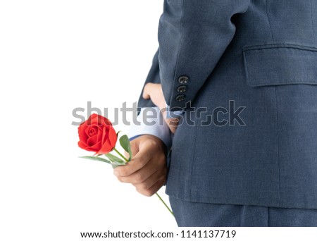 Close up photo of businessman in suit  holding red roses behind his back on white background