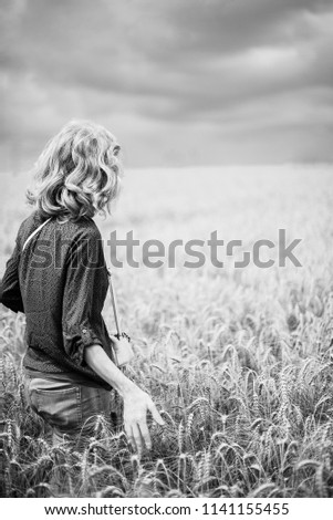 woman in a wheat field. year-old black and white landscape. the figure of the girl in the ears of wheat. Royalty-Free Stock Photo #1141155455