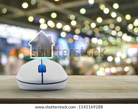 House icon with copy space with wireless computer mouse on wooden table over blur light and shadow of shopping mall, Real estate concept