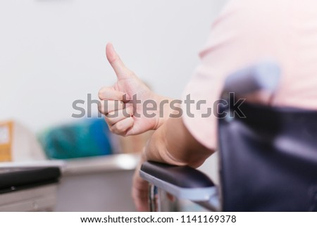 Close up of male patient on wheelchair giving thumbs up as a sign of happy support