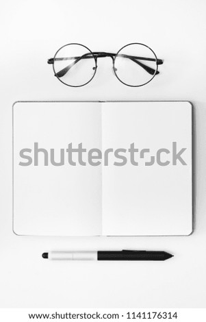 eyeglasses and note with empty pages on white background