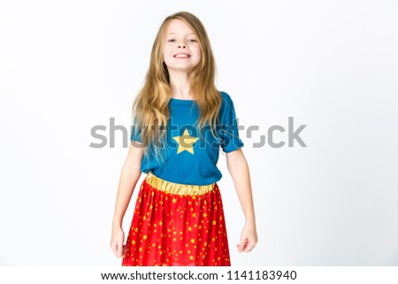 young, blond girl is dressed as a supergirl in the studio