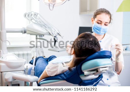 Dentist treats teeth girl lying in the dental chair Royalty-Free Stock Photo #1141186292