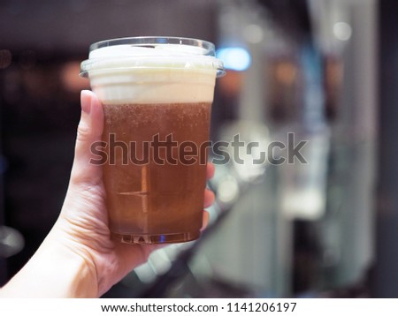 A plastic glass of iced oolong tea (also called wulong or wu long) with layer of cream cheese foam, Traditional Chinese Beverage. Selective focus.