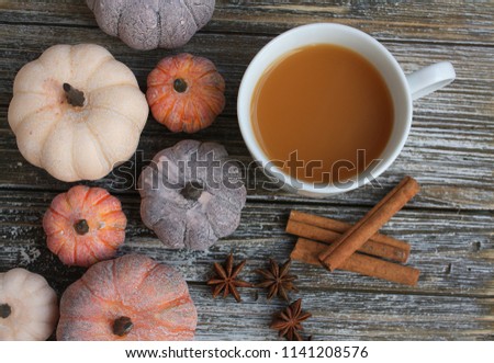 colorful aged pumpkins on the left with a white mug of coffee. Also star Anise and cinnamon sticks. On a rustic wooden background. 
