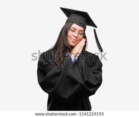 Young hispanic woman wearing graduated cap and uniform sleeping tired dreaming and posing with hands together while smiling with closed eyes.