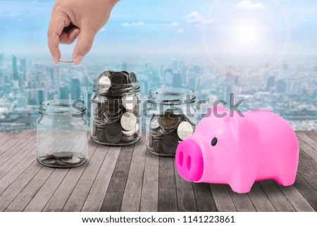 Male hand putting money coins in clear bottle, piggy bank on wooden Plank and green nature blending cityscape background concept business finance of money growth, prepare in the future or saving