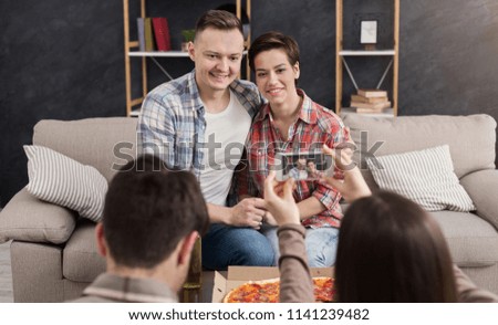 Woman taking photo of couple with mobile phone at home