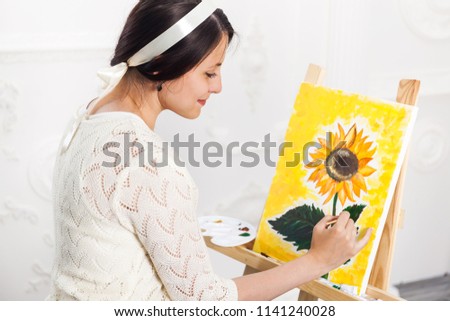 Getting creative. Woman artist painting a sunflower in art studio