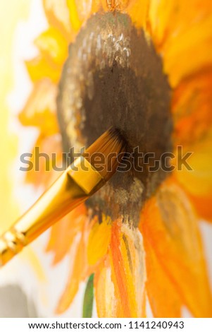Artist's hand with brush painting a picture Sunflower