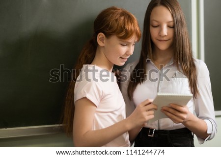 student girls are sitting at a Desk and learn in school, free University