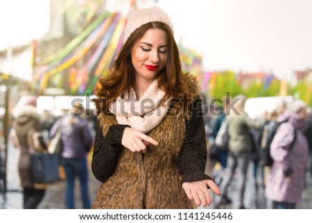 Girl with winter clothes holding something on unfocused background
