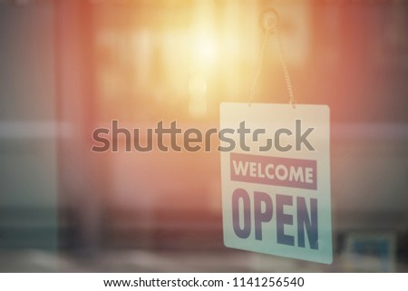 Open and welcome sign broad through the glass of window to let customers know