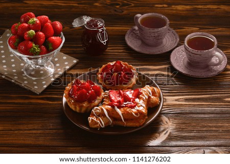 Tea drinking with tartlets and cakes with strawberries