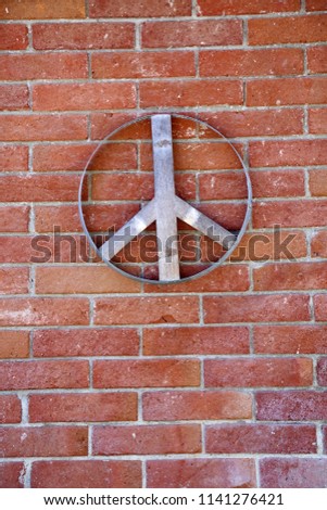 Peace Sign. A wooden peace sign on a brick wall outdoors. 