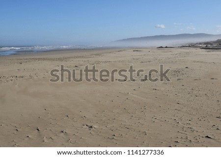 Sand dunes against a misty mountain backdrop. 