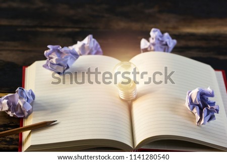 Concept idea. Growing light bulb on vintage book with crumpled papers and pencil. Copy space for your text. conceptual great ideas are always available. Creative thinking.