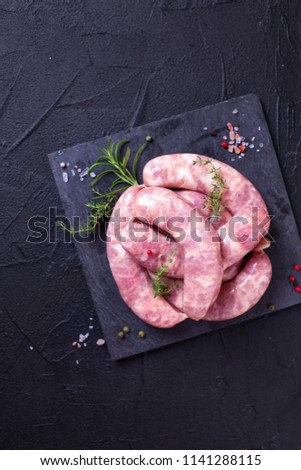 Fresh homemade raw sausages os slate board on black textured background. Top view.Selective focus. Place for text. Vertical image.
