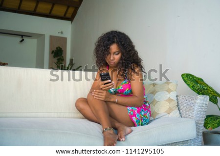 lifestyle portrait of young happy and gorgeous black african american woman at home living room using internet mobile phone networking and texting relaxed on couch enjoying social media 