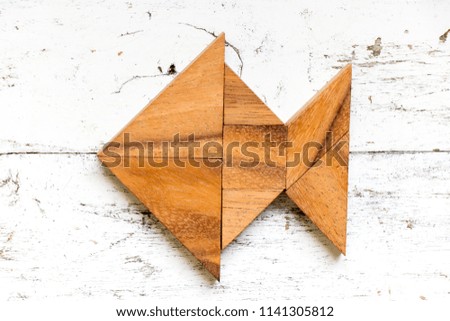 Tangram puzzle in fish shape on old white wood background