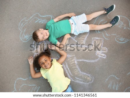 Little children lying near chalk drawing of airplane on asphalt, top view