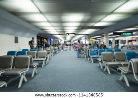 Blur background of seats row at Terminal Airport for waiting flight departure with blurry passenger who sit on chair with luggage.