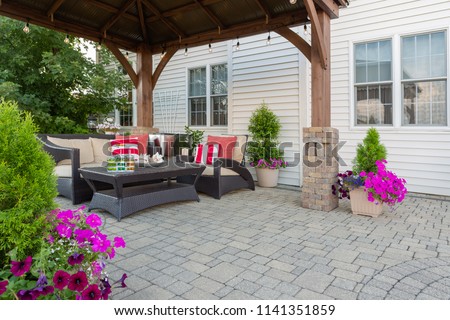 Brussel block design pavers on an exterior patio and summer living space with a covered gazebo, colorful petunias and comfortable seating Royalty-Free Stock Photo #1141351859