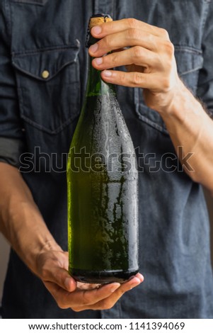 Male hands holding corked bottle of premium cidre. Beautiful ice cold bottle of apple wine in man's hands Royalty-Free Stock Photo #1141394069
