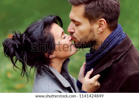 Smiling young girl and handsome man kisses. Beautiful couple hug in the park. Happy family. Sweethearts. Love story. Tender relationship. Valentine's day
